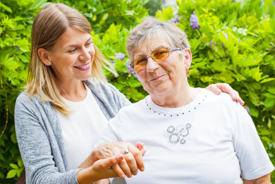 caregiver holding the hand of a senior woman