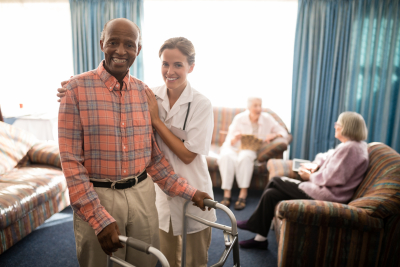 caregiver assisting senior man to use walker