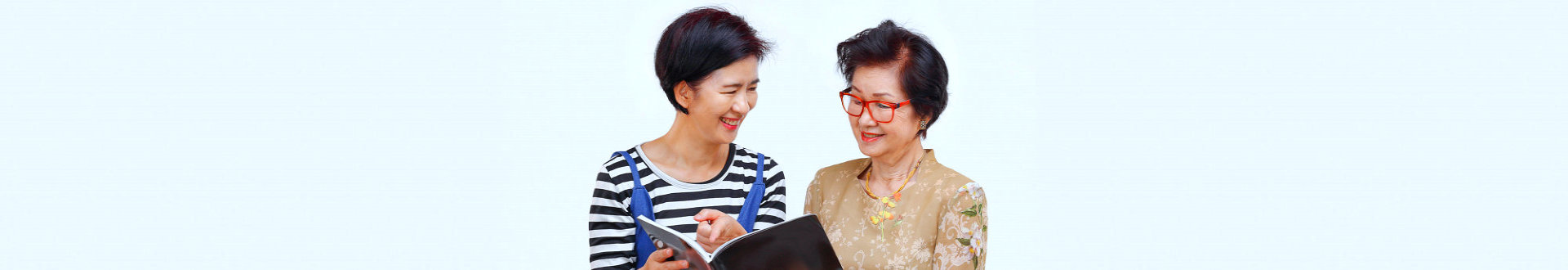 caregiver reading a senior woman's bok